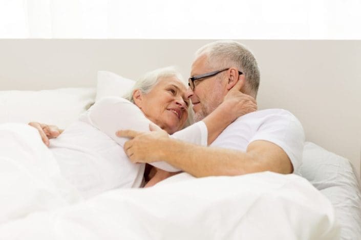 An older couple in bed cuddling