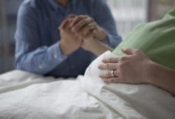 Man holding hand of pregnant woman in hospital bed