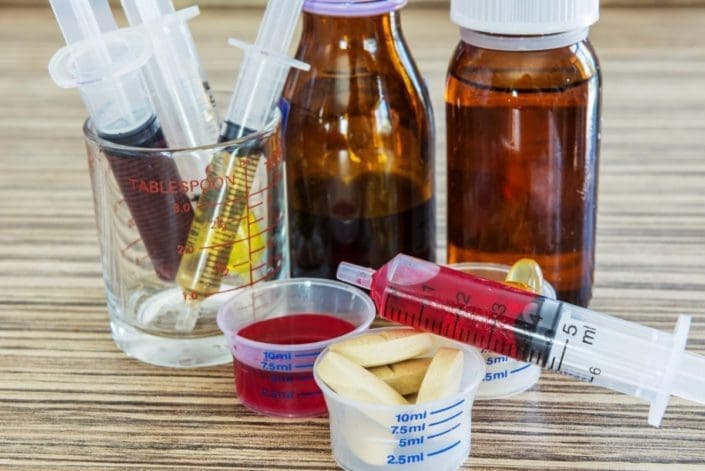 Bottles of liquid medicines and pills sitting on counter