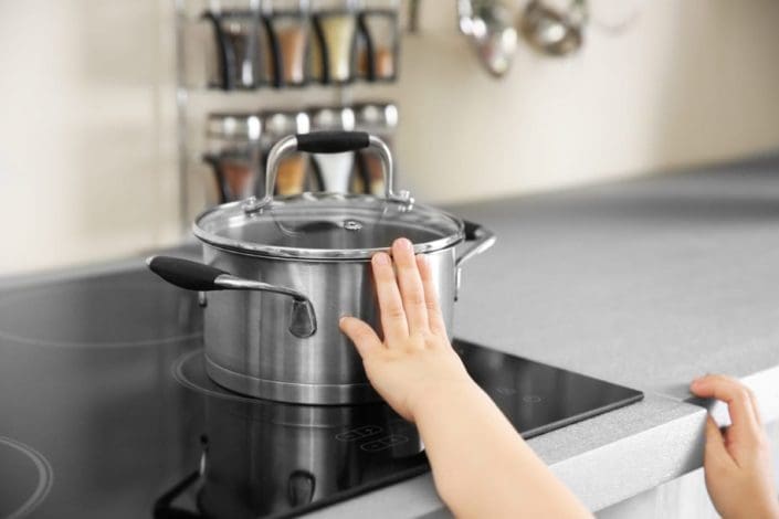 Young child touching hot pot on the stove