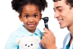 Little girl smiling as doctor examines her ear