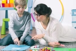 Female therapist working with young boy on floor