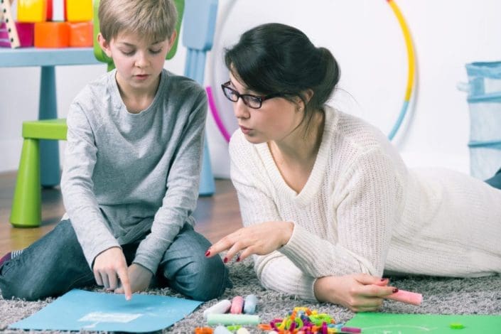 Female therapist working with young boy on floor