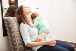Tired mom naps while holding a sleeping baby at home. Postpartum recovery takes time, as your body has been through a trauma. Fully recovering from pregnancy and childbirth can take months.