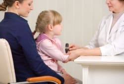 Little girl sitting in mother’s lap at doctor’s office