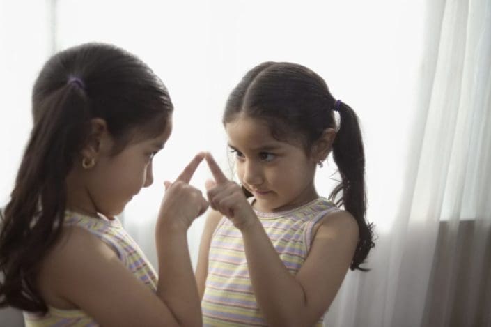 Young girl looking at her reflection in the mirror