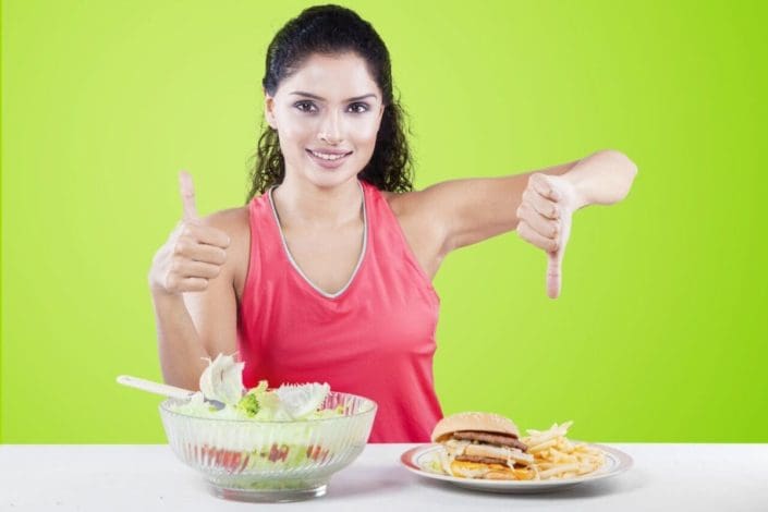 Woman giving thumbs up to salad and thumbs down to burger