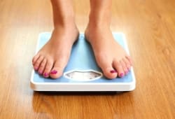 A person stands on a scale. Our BMI calculator can help measure your weight relative to your height and functions as a rough estimate of body fat.