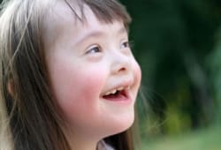 a young girl with Down syndrome looks up and smiles