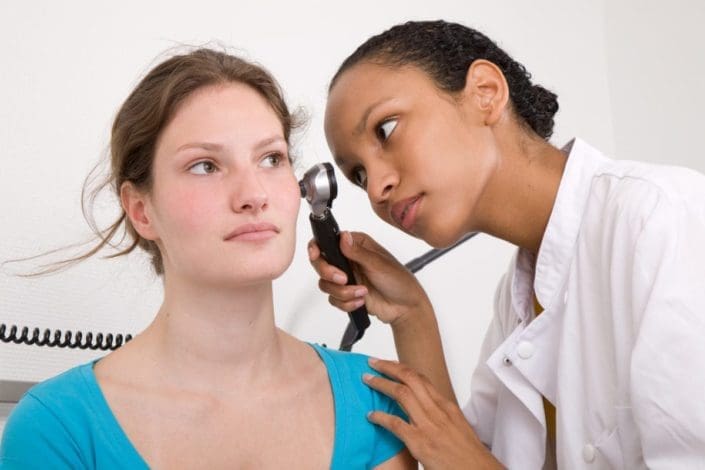 Doctor examining patient’s ear with otoscope