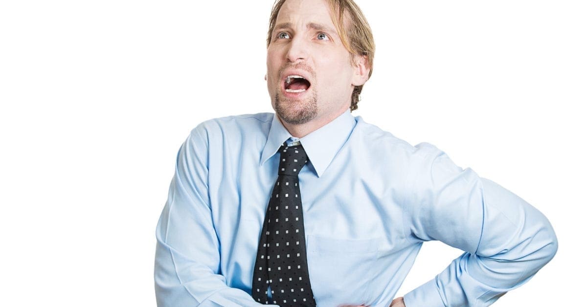 Close-up of a young businessman holding side with kidney pain
