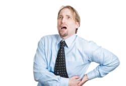 Close-up of a young businessman holding side with kidney pain