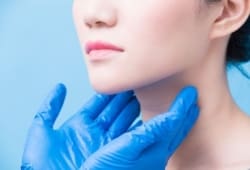 two hands wearing rubber gloves and feeling a woman's lymph-nodes in her neck to test for non-hodgkin lymphoma