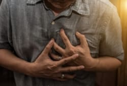 Man clutching chest in pain as a result of coronary heart disease
