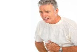 A man suffering from an ulcer clutches his abdomen in pain. An ulcer is a sore on the lining of your stomach or small intestine. Ulcer symptoms include stomach pain, bloating and feeling full fast.
