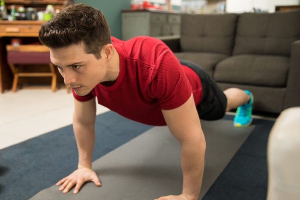 Close-up of a young man doing push ups on an exercise mat at home