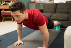 Close-up of a young man doing push ups on an exercise mat at home