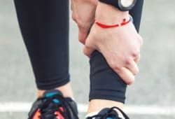 Woman runner holding shin in pain