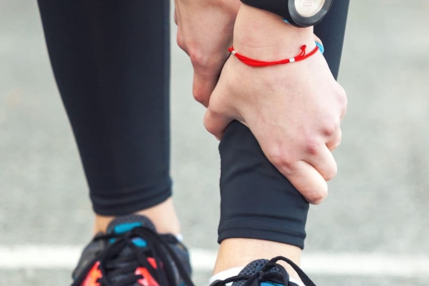 Woman runner holding shin in pain