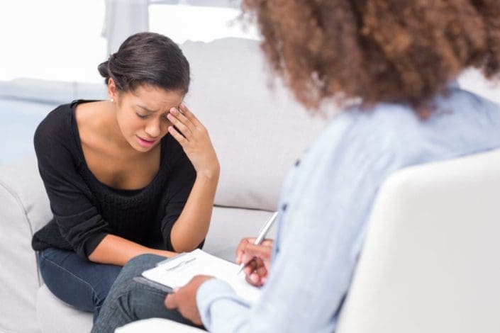 Upset woman sitting on couch talking with a counselor