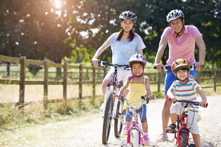 family of four wearing helmets and riding bicycles together