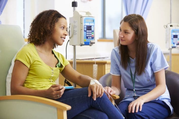 woman sits with a nurse while receiving chemotherapy treatment
