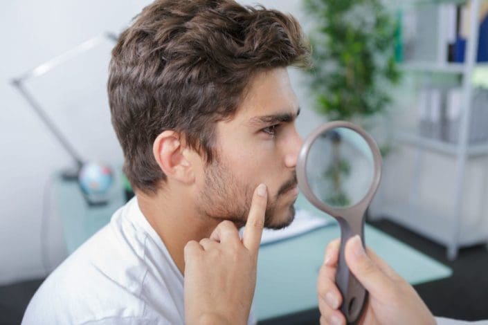 close-up of doctors hands checking man’s moles
