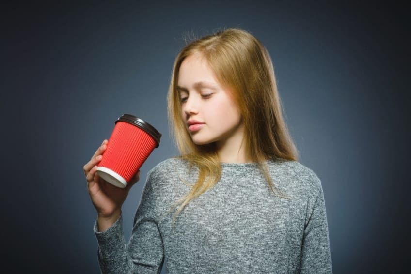 eenage girl sipping from to-go coffee cup