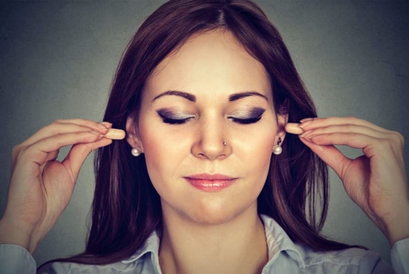 A young woman putting earplugs in her ears