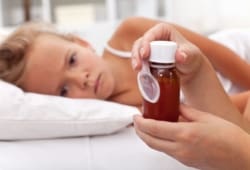 child lying in bed waiting to take medicine