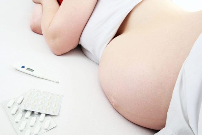 Ill pregnant woman lying on bed