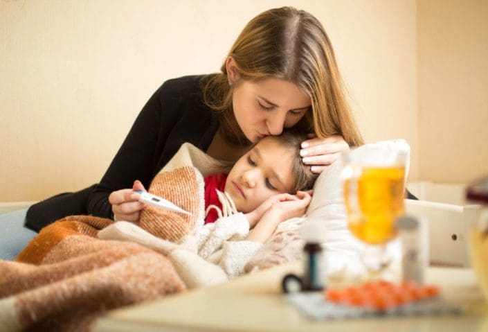A young caring mother kisses her sick daughter's head. Cold and flu season often begins in October as the weather outside starts to turn cold. It can last until May. Each year, it’s important to prepare and protect your family from these illnesses.