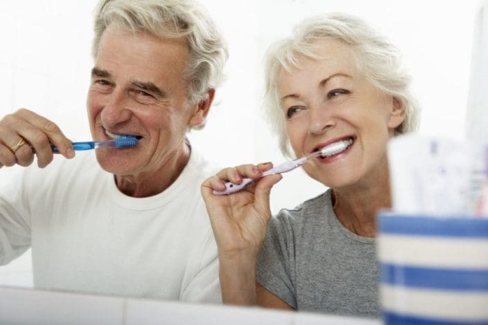 senior couple brushing their teeth