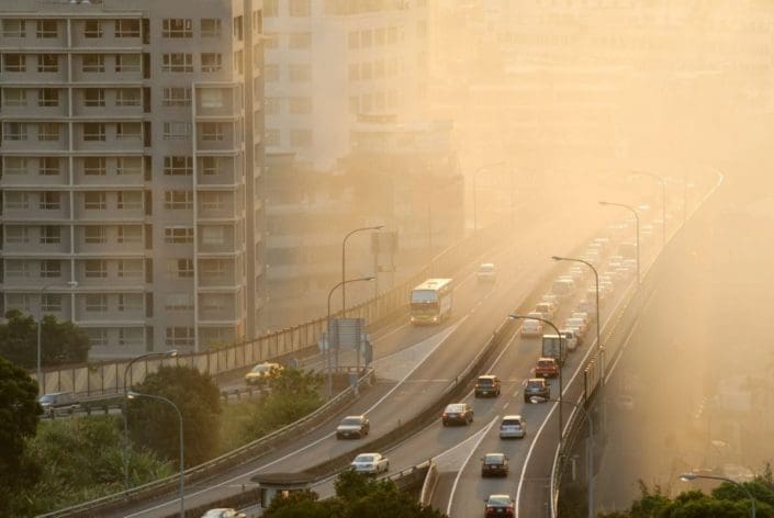Air pollution scenic with cars on highway and yellow smoke in city