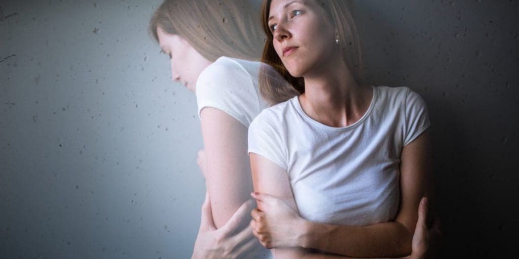 Young woman suffering from depression/anxiety stands with her arms crossed.