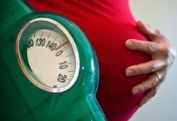 pregnant woman holding scale with other hand on her belly