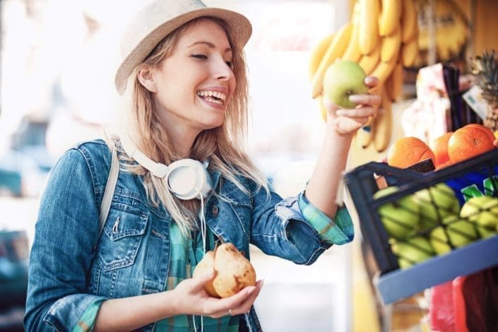 young woman is looking for pear and apple at green market