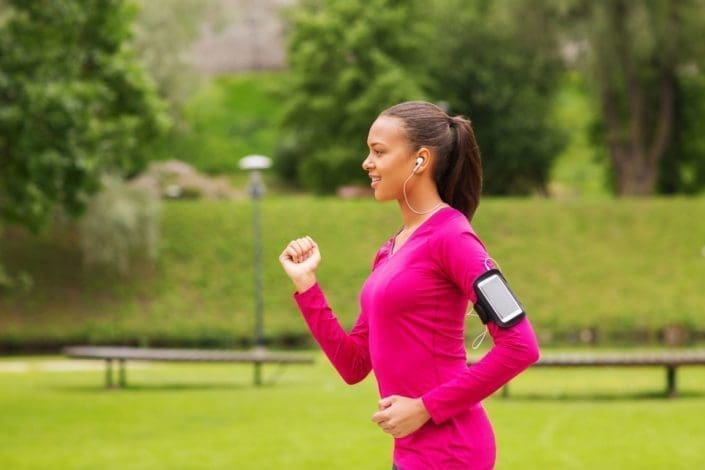 young woman exercises outdoors with smartphone and earbuds