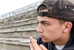 Teenage boy smoking cigarette outside