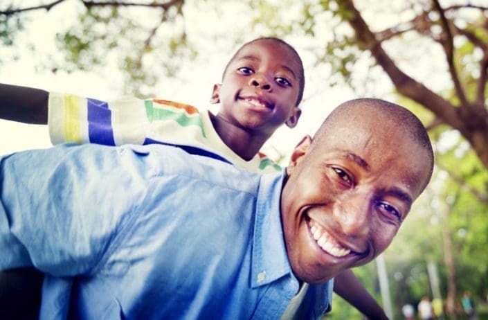 smiling father gives son a piggy-back ride outside