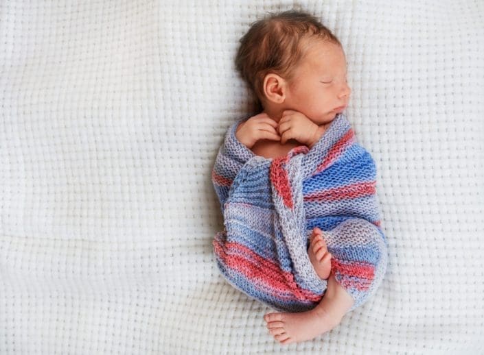 newborn baby wrapped up in a blanket sleeping
