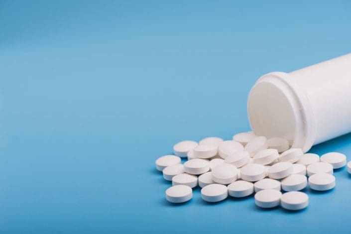 Bottle of white pills spilled out onto a table