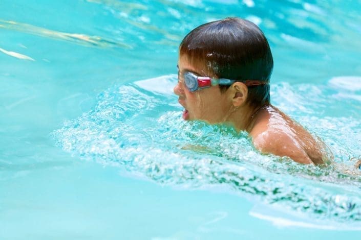 Close up of young boy swimming in pool