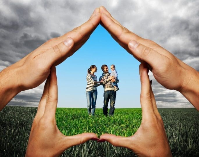 hands in the shape of a house protecting young family
