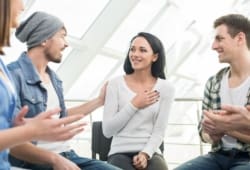 group of people are sitting in circle and supporting each other