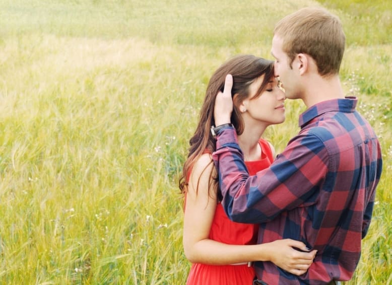 sensual outdoor portrait of young attractive couple in love kissing in summer field
