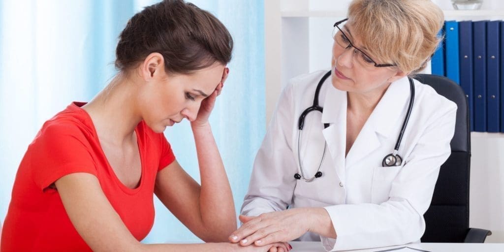 Doctor holds the hand of a depressed female patient.