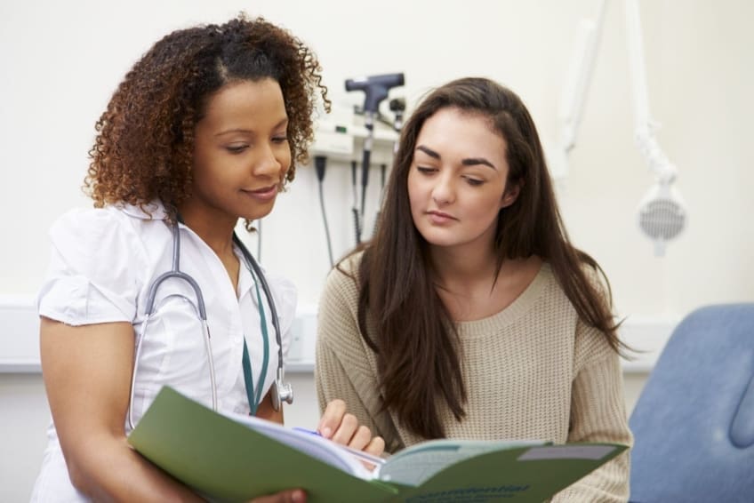 A nurse showing a patient test results from a preventive test, on a digital tablet