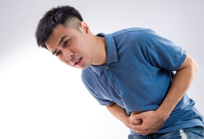 A men bent over clutching his side in pain due to appendicitis symptoms.
