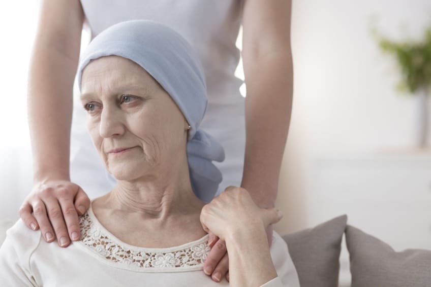 A crying elderly woman with cancer is comforted by a caretaker. Pancreatic cancer is an abnormal growth of cells in the pancreas. It is difficult to detect early, making treatment tough at later stages.